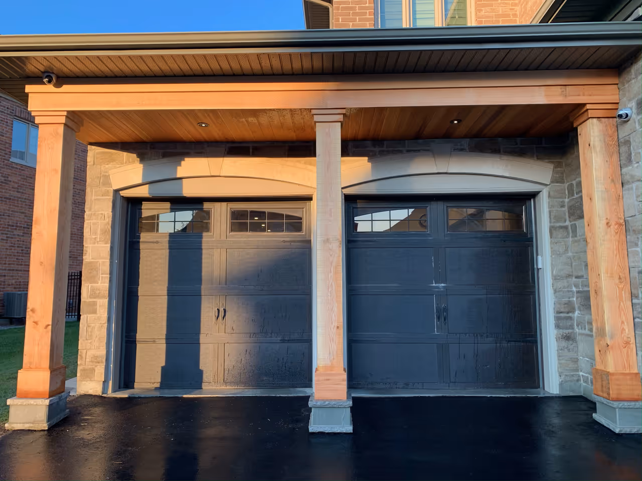 Two garages with wooden columns and a wooden door, providing ample space for parking and storage.