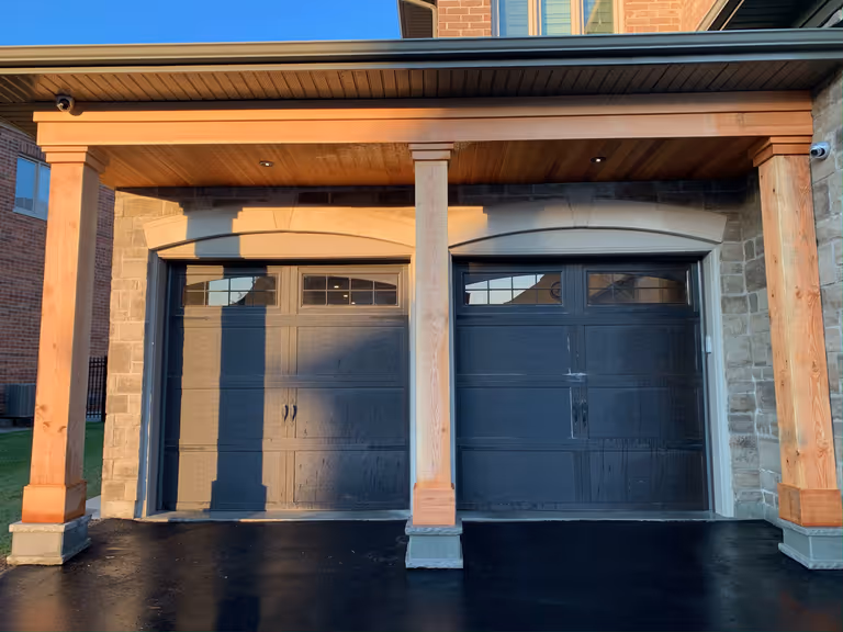 Two garages with wooden columns and a wooden door, providing ample space for parking and storage.
