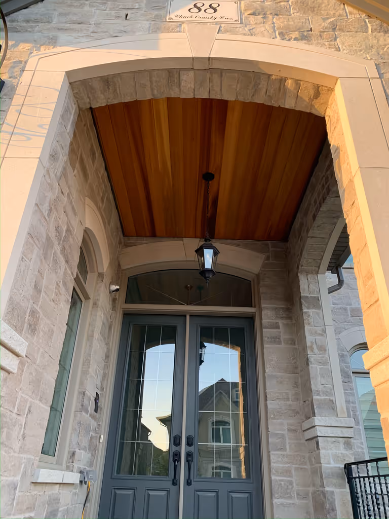 A door with a sizable window, allowing ample light to pass through covered by a stained wood ceiling.
