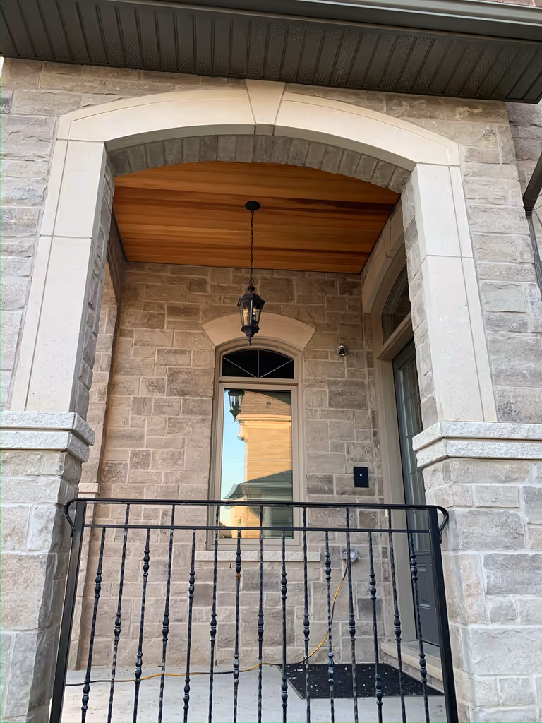 A door with a window and a railing covered by a stained wood ceiling.