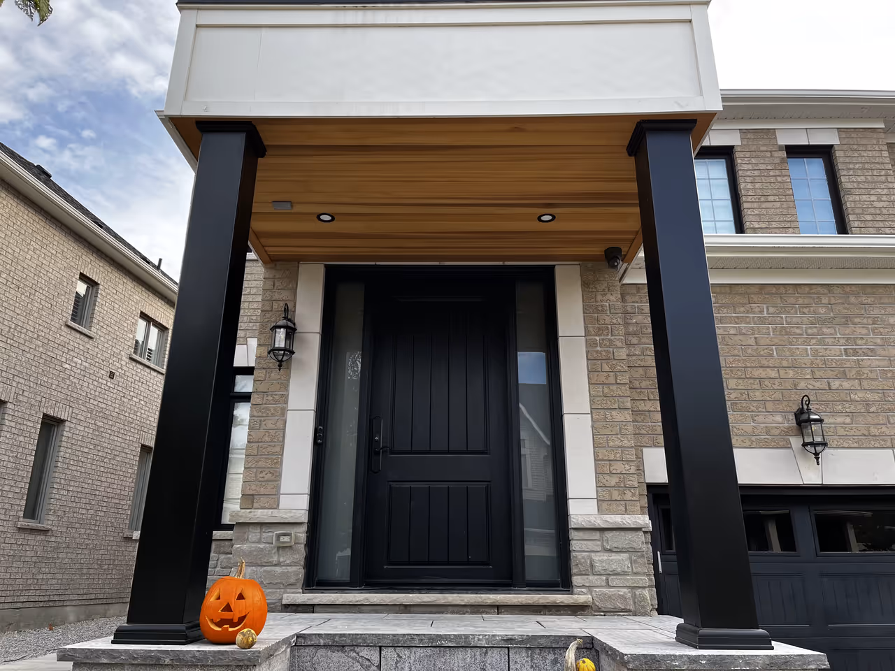 A columned roofed front entrance with a stained natural wood accent ceiling.