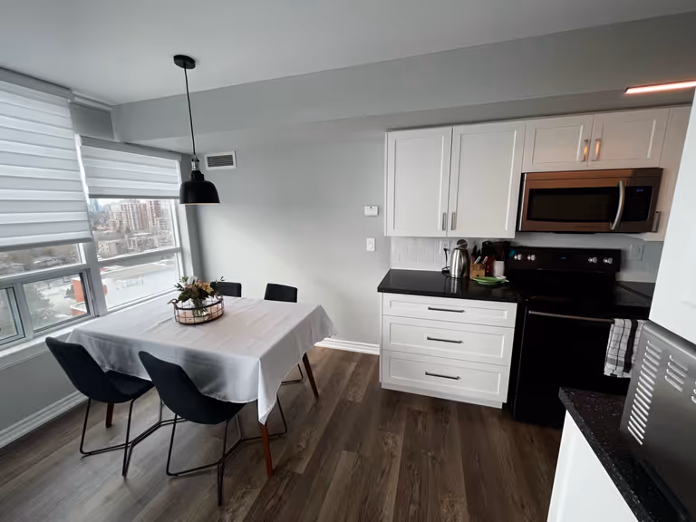 A kitchen with a table, chairs, and a microwave.