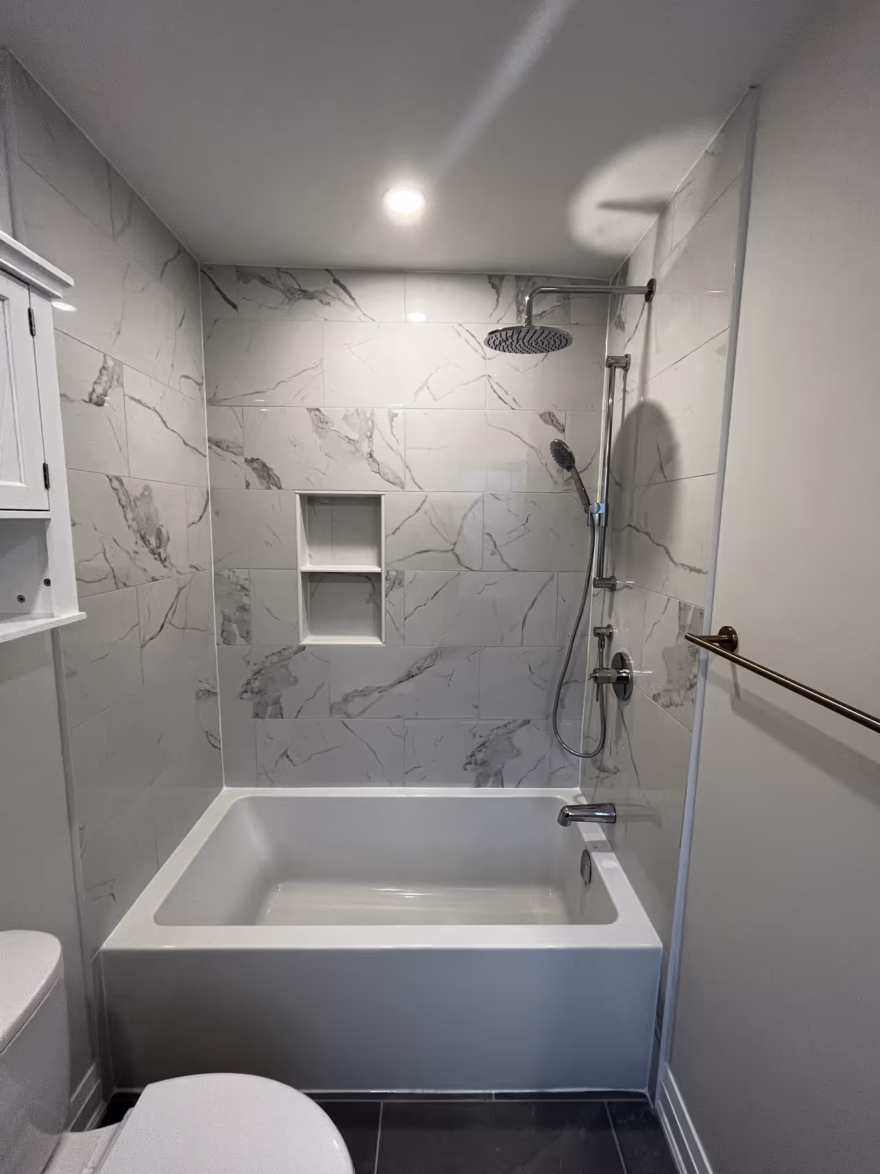 A bathroom showcasing a pristine white tub and shower, offering a serene and refreshing space for relaxation and personal hygiene.