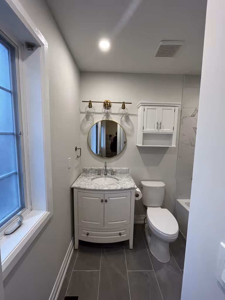 A bathroom featuring a white vanity and toilet.