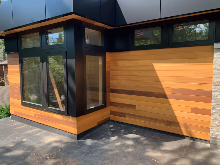 A stylish home featuring wood paneling and expansive windows.