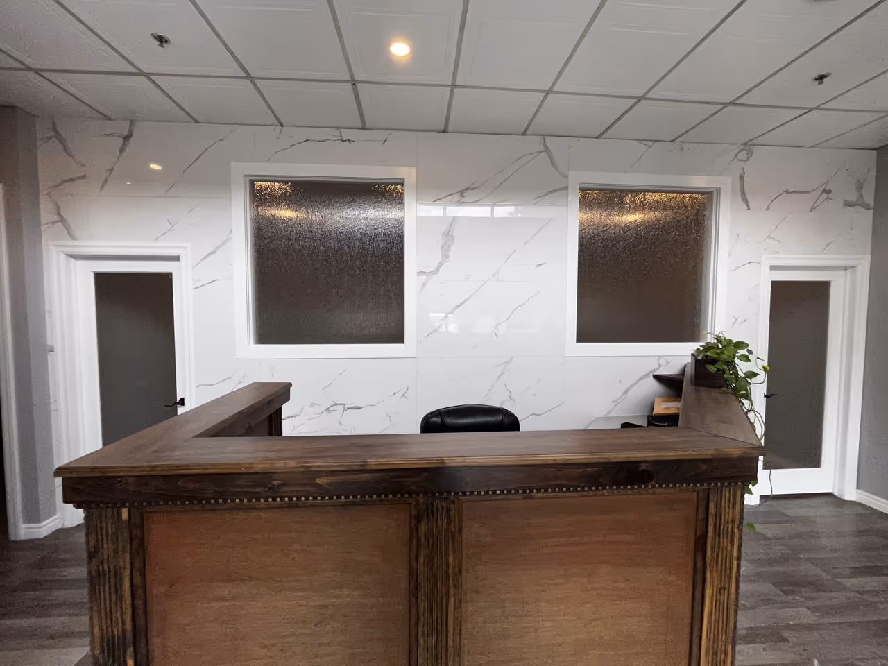 Modern office reception area with elegant marble walls and desk.