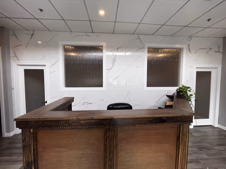 Modern office reception area with elegant marble walls and desk.