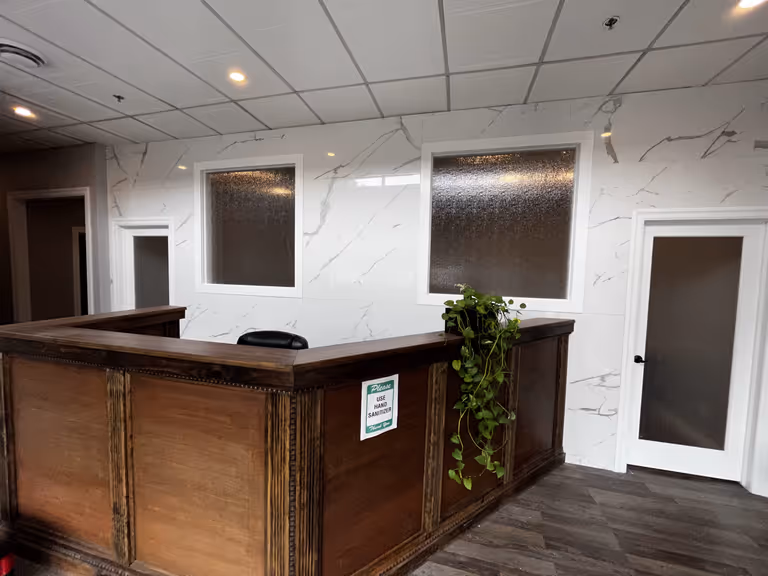 Modern office reception area with elegant marble walls and desk.
