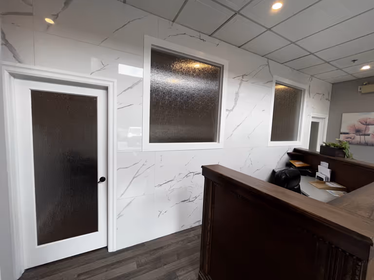 Modern office reception area with elegant marble walls and desk.